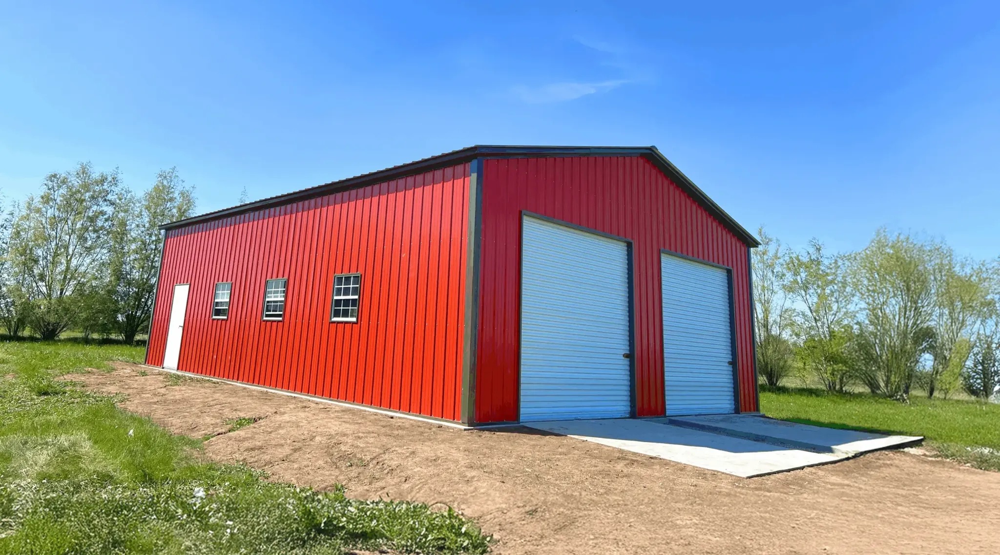 Large red metal building with roll-up doors and windows