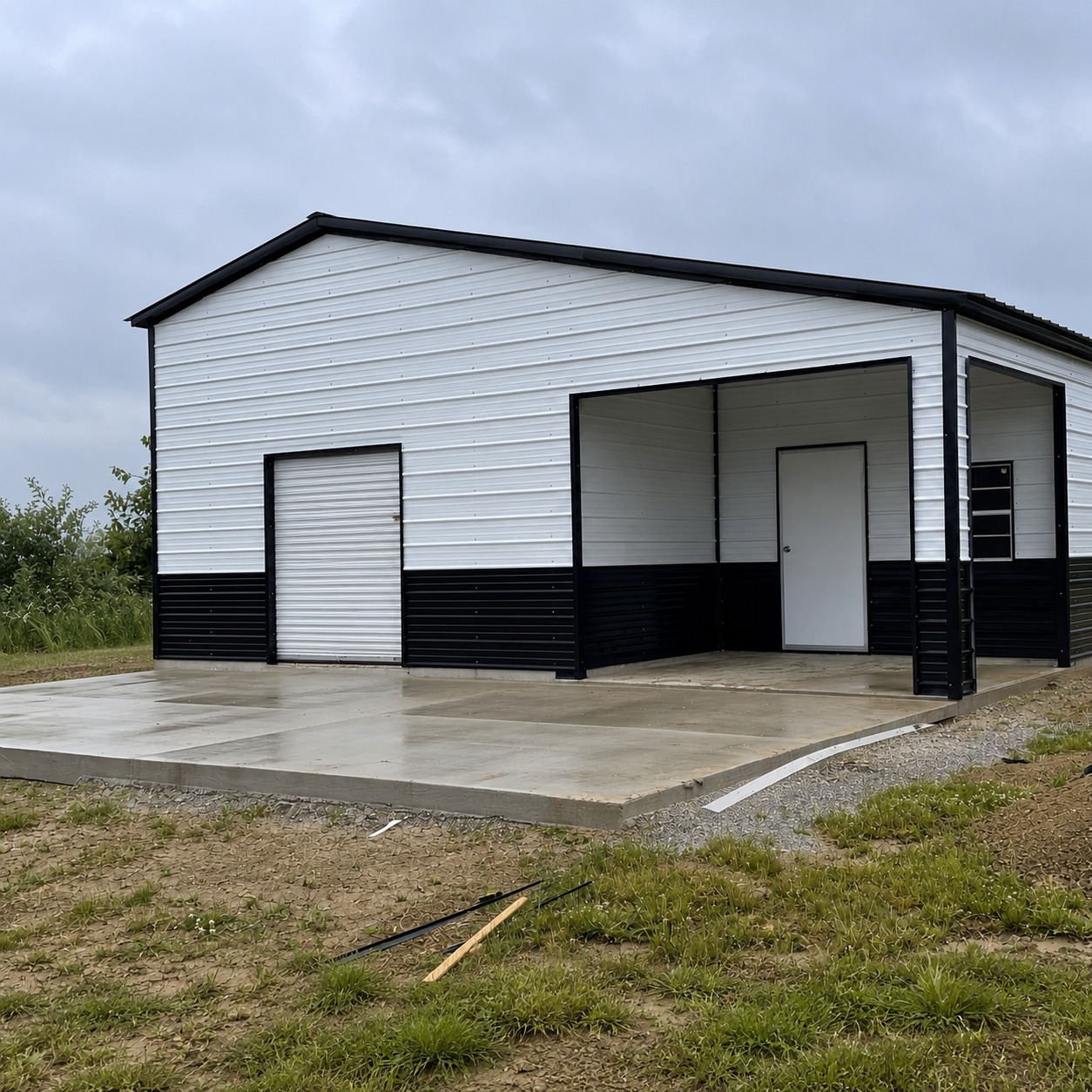 White and black enclosed garage with covered patio on concrete pad